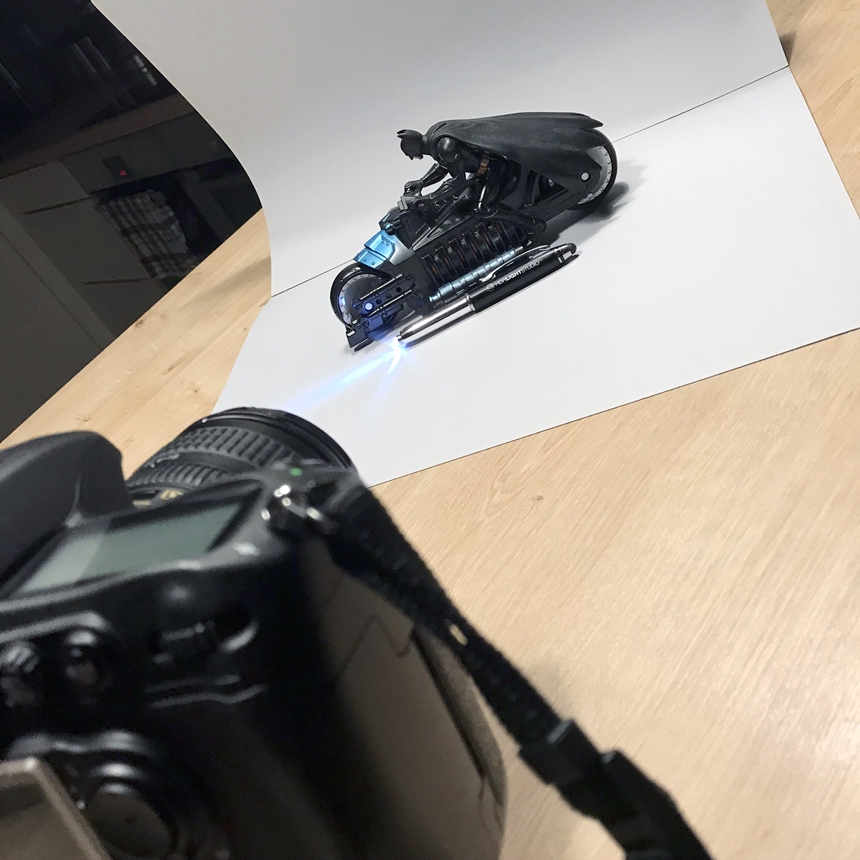 DSLR on mini tripod, grey card backdrop, LED torch pen and Batman Toy
